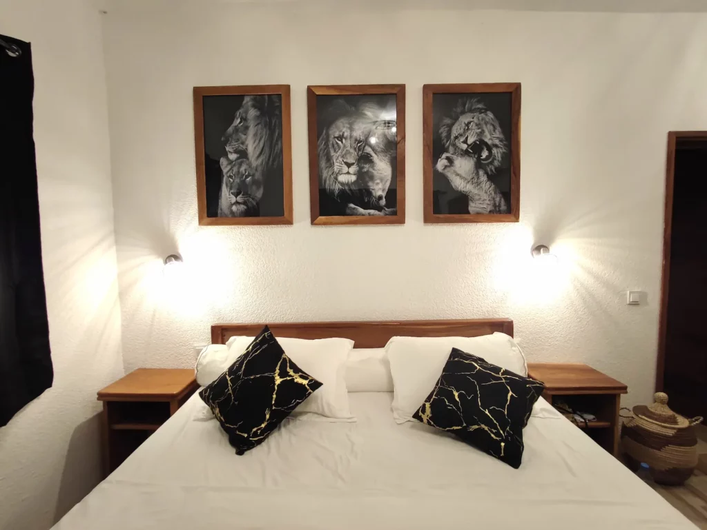 Laissez-vous envoûter par cette fresque murale. La lionne, le lion et le lionceau imposent le respect. Scènes authentiques encadrées dans des tableaux, décorant la chambre numéro 1 du Campement Houéfa.