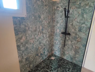 Photo du vaste espace douche de la chambre numéro 3. Douche à l'italienne, carrelage bleu azur et paroi vitrée.
