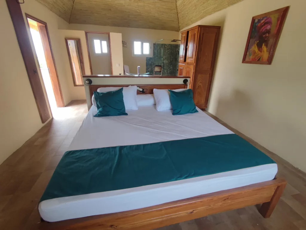 Le Campement Houéfa compte deux villas, avec chacune 3 chambres. Photo de la chambre numéro 3 avec son lit King size, sa tête de lit séparant l'espace nuit de l'espace salle de bain.