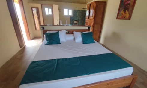 Le Campement Houéfa compte deux villas, avec chacune 3 chambres. Photo de la chambre numéro 3 avec son lit King size, sa tête de lit séparant l'espace nuit de l'espace salle de bain.