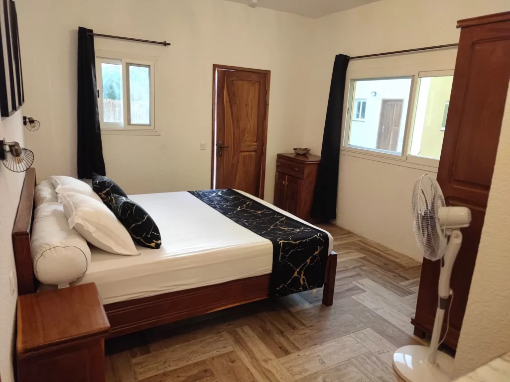 Le Campement Houéfa compte deux villas, avec chacune 3 chambres. Photo de la chambre numéro 5 en rez-de-chaussée, disposant de vastes fenêtres laissant entrer la lumière, avec moustiquaires et rideaux occultant si nécessaires.