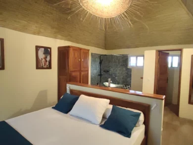 Le Campement Houéfa compte deux villas, avec chacune 3 chambres. Photo de la chambre numéro 6 avec son lit King size, sa tête de lit séparant l'espace nuit de l'espace salle de bain.