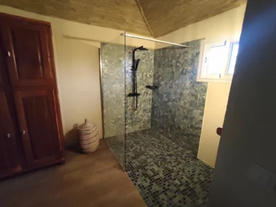 Le Campement Houéfa compte deux villas, avec chacune 3 chambres. Photo du vaste espace douche de la chambre numéro 6. Douche à l'italienne, carrelage bleu azur et paroi vitrée.