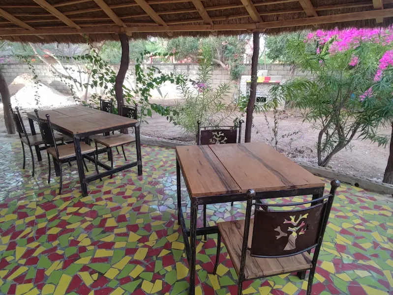 Au Campement Houéfa le petit-déjeuner est servi en terrasse sur des tables en fer forgé et bois local. Le dossier de la chaise reprend la forme du baobab.