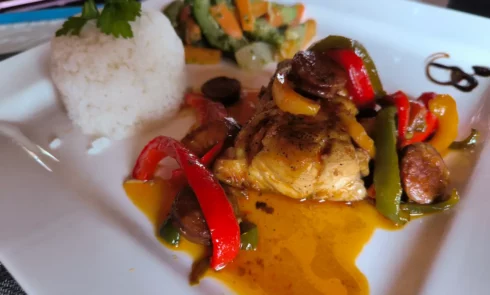 A proximité du Campement Houéfa, vous pourrez déguster des plats traditionnels sénégalais voire gastronomiques. L'image représente une assiette garni du poisson du jour avec une sauce raffinée aux poivrons, bananes plantins, accompagnée de riz blanc et de légumes sautés.